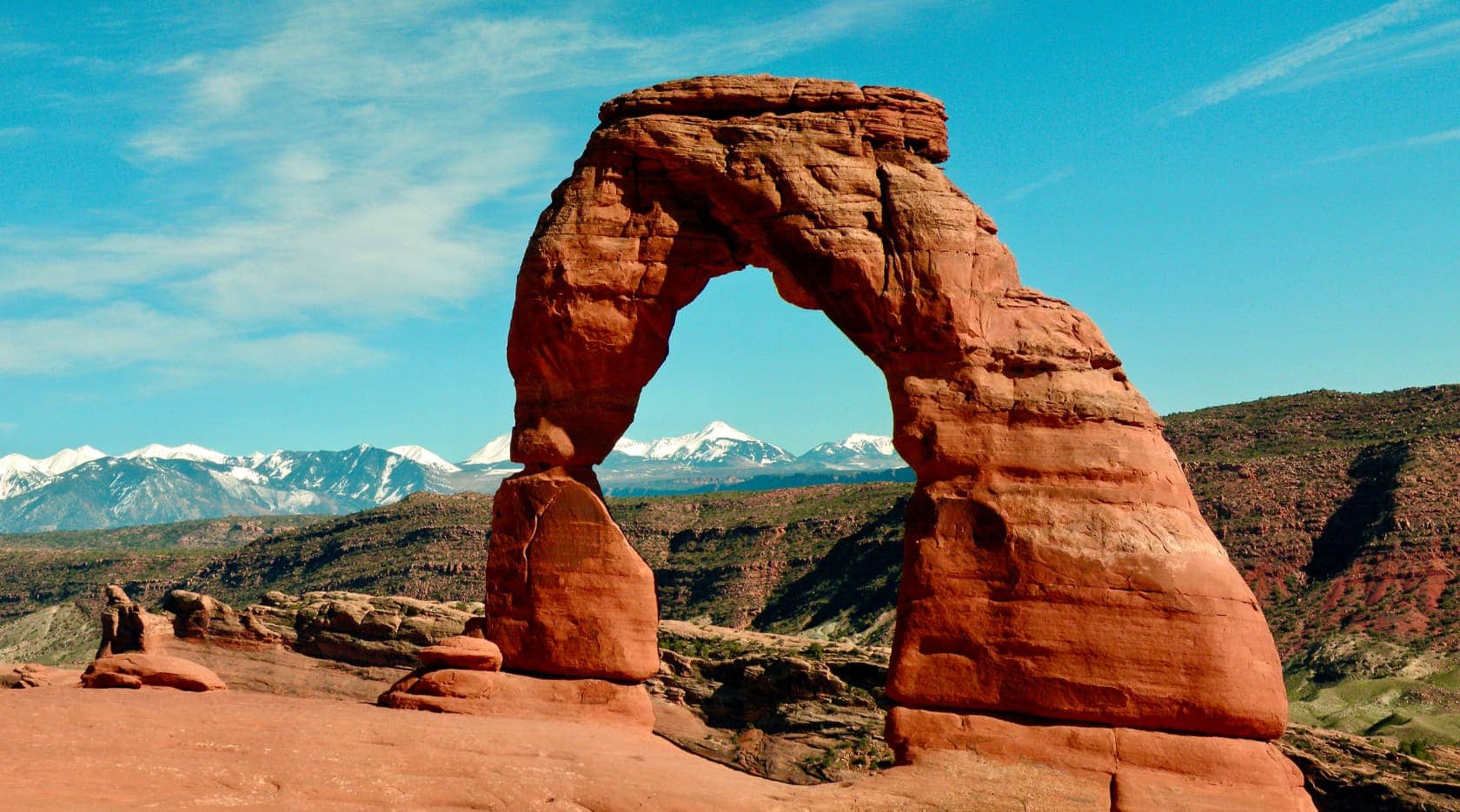 Red rock archway and snow covered mountains in the distance