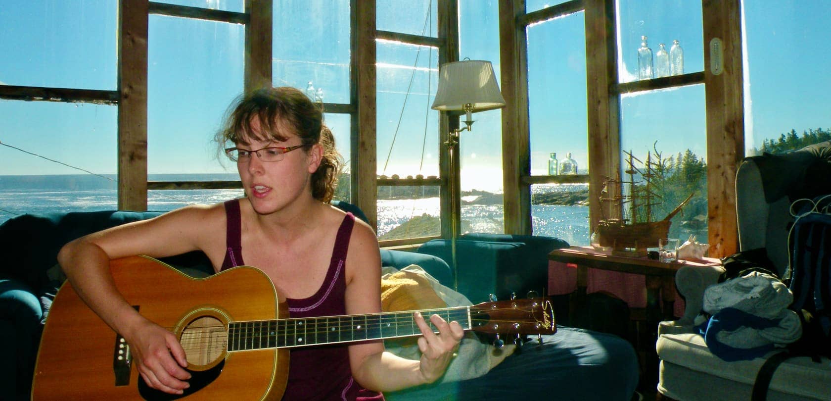 Woman playing acoustic guitar in glass window house