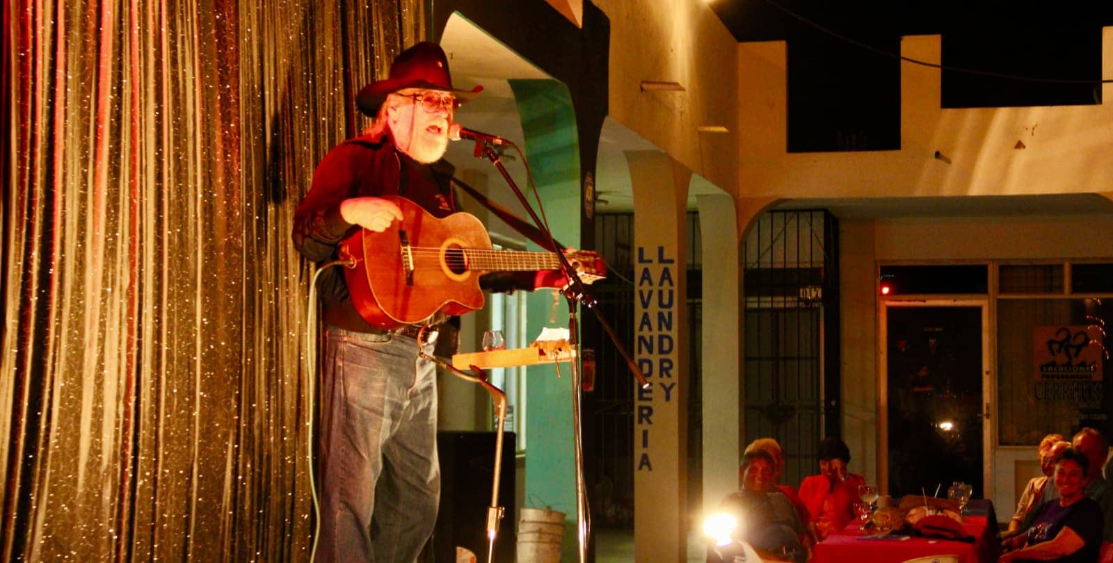 Elderly beareded man singing with acoustic guitar