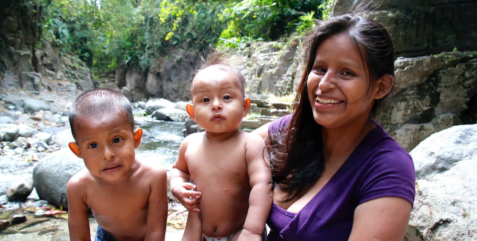 Mother with two young children along river in Panama