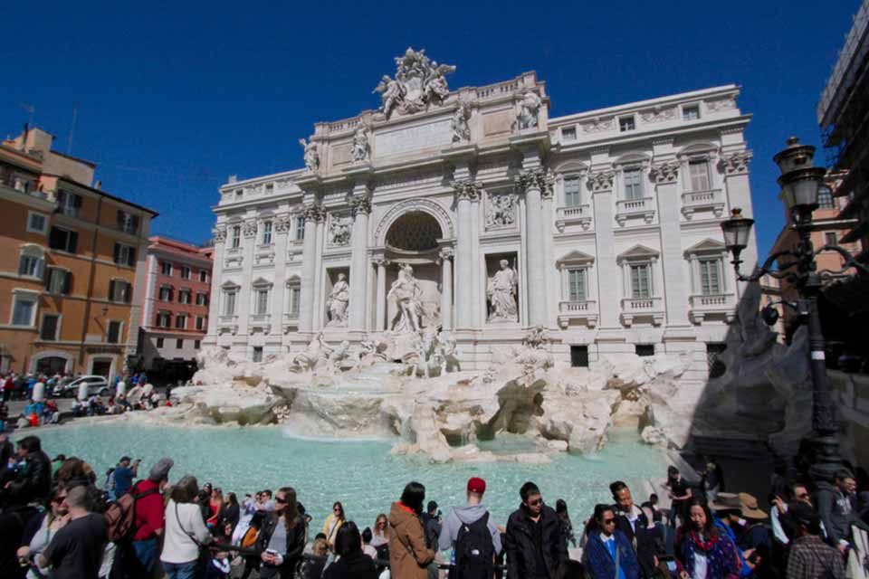 Building with statues, water fountain, and people