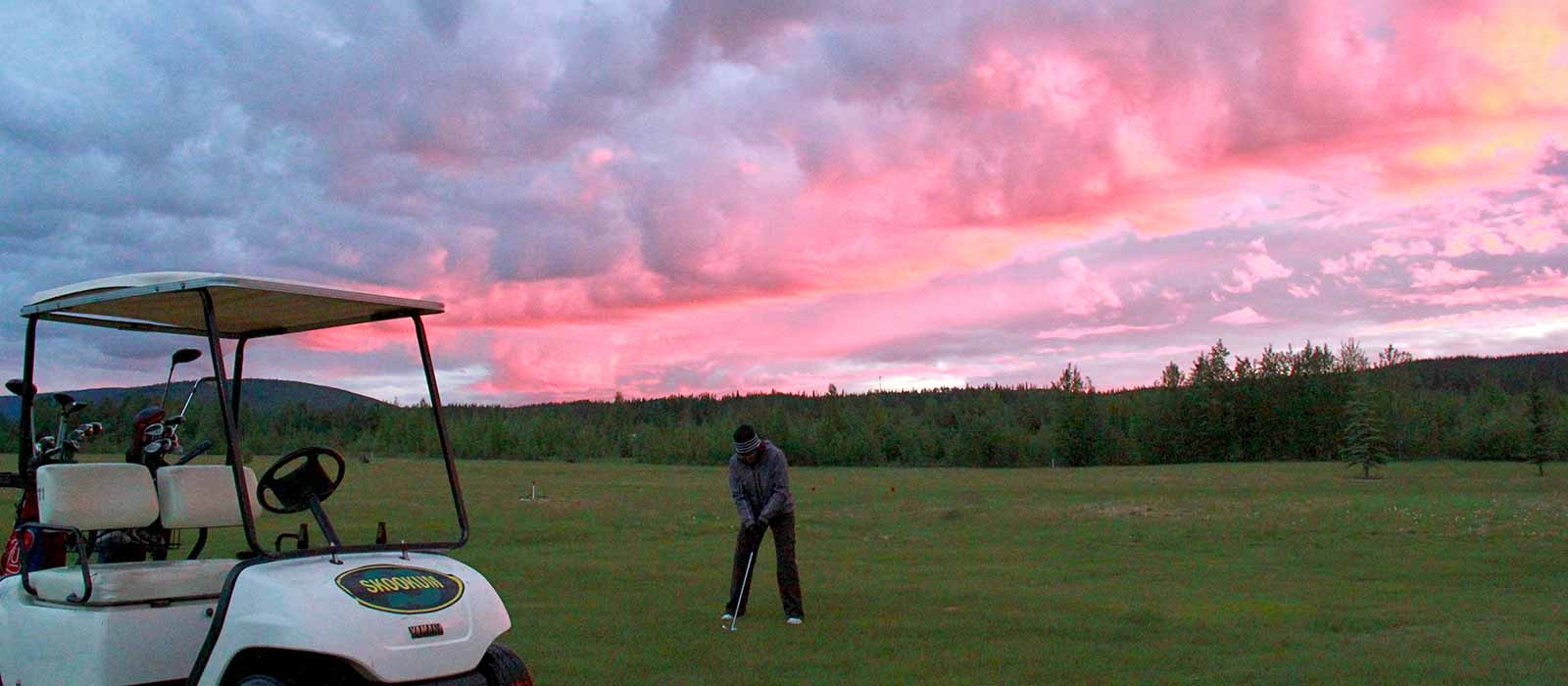 Person golfing under red sky