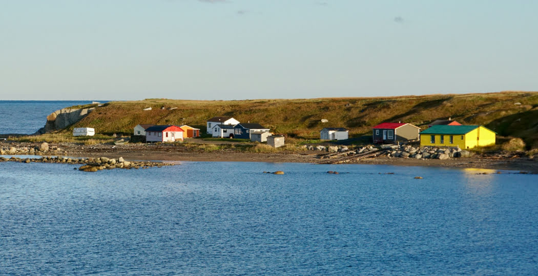 A body of water with different coloured houses sitting on the shore