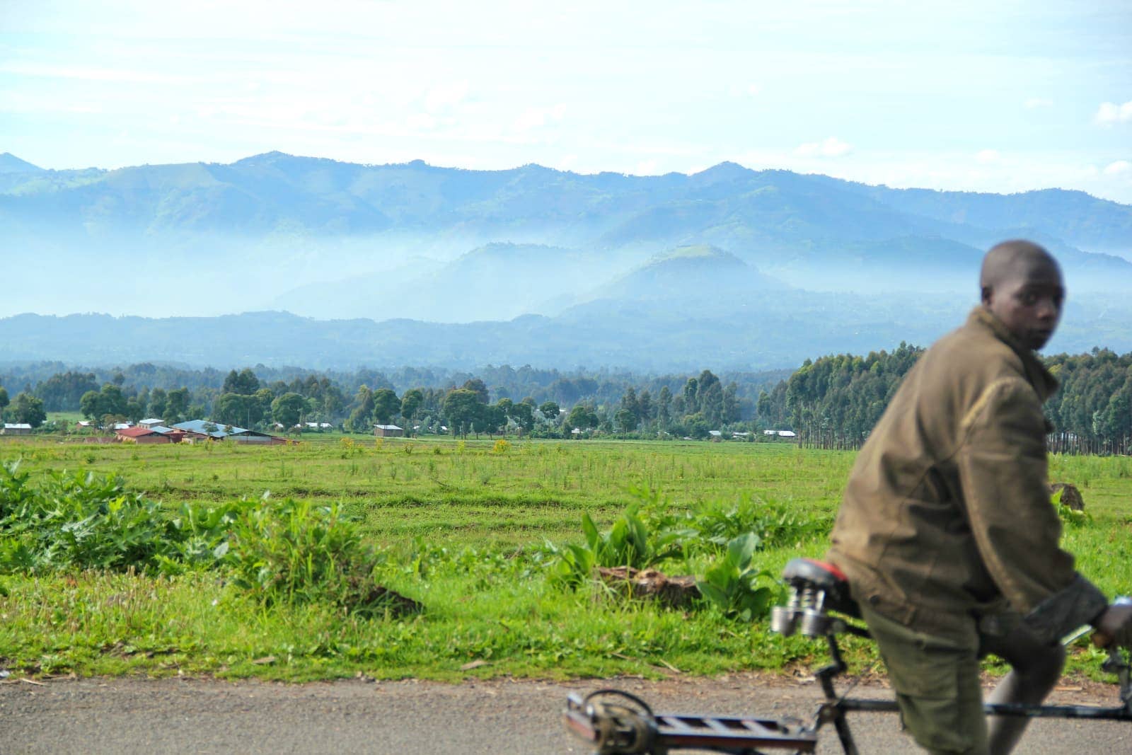 African man on bicycle in foreground with mountains in background