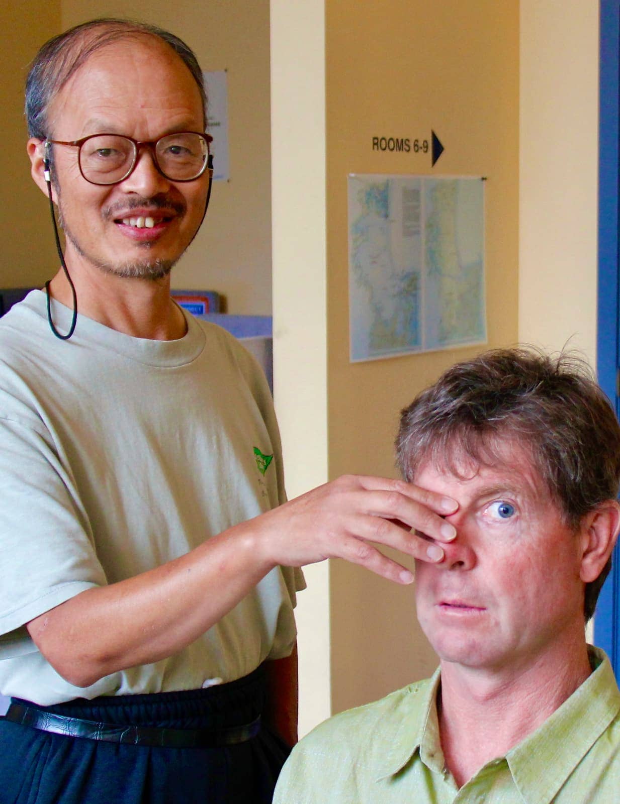 Asian man with hand over another man's eye