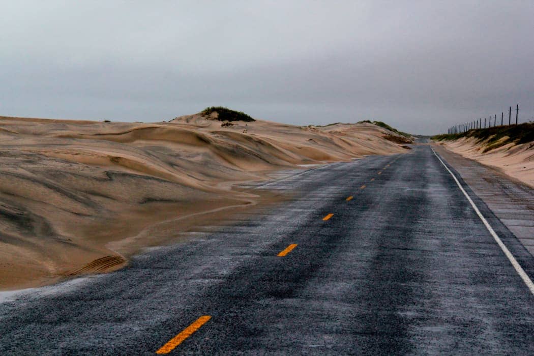 Beige sand encroaching onto highway