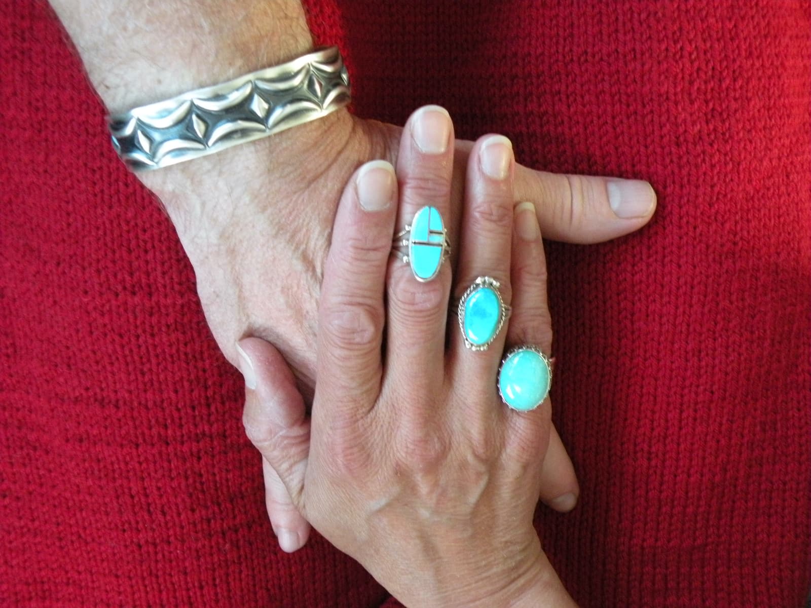 Blue rings on one hand covering a second hand