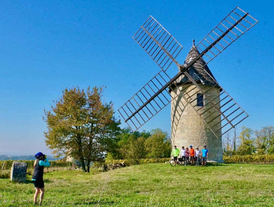 Cyclists posing in front of large windmill