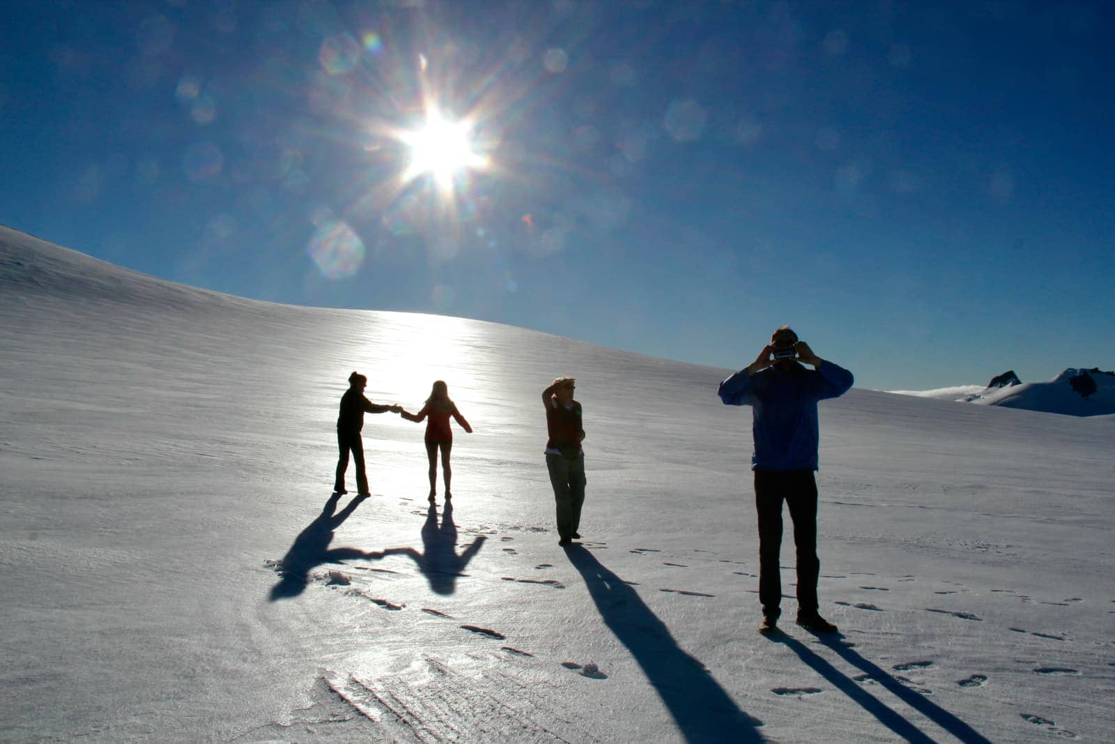 Four people standing on snow covered mountain