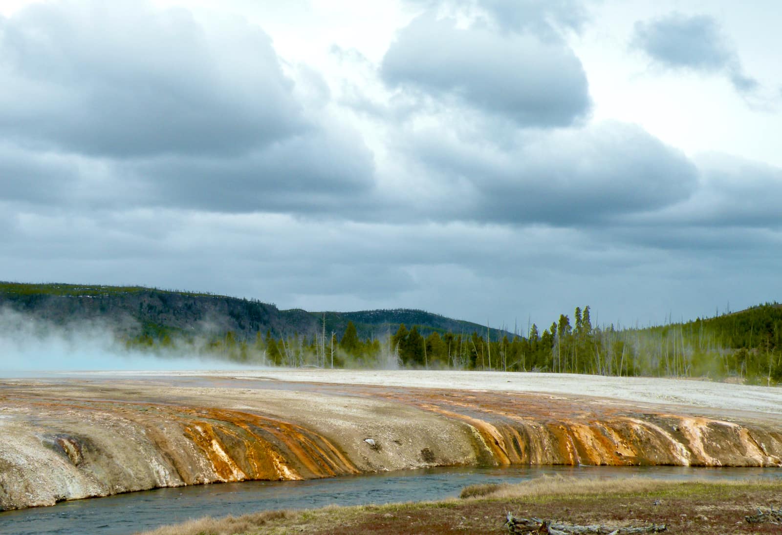 Geothermal formation and river in foreground with clouds in background