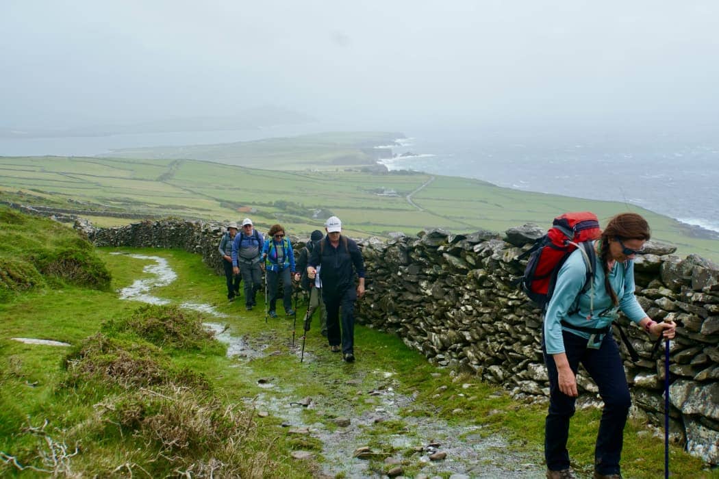 Group hiking uphill in rain along coastline