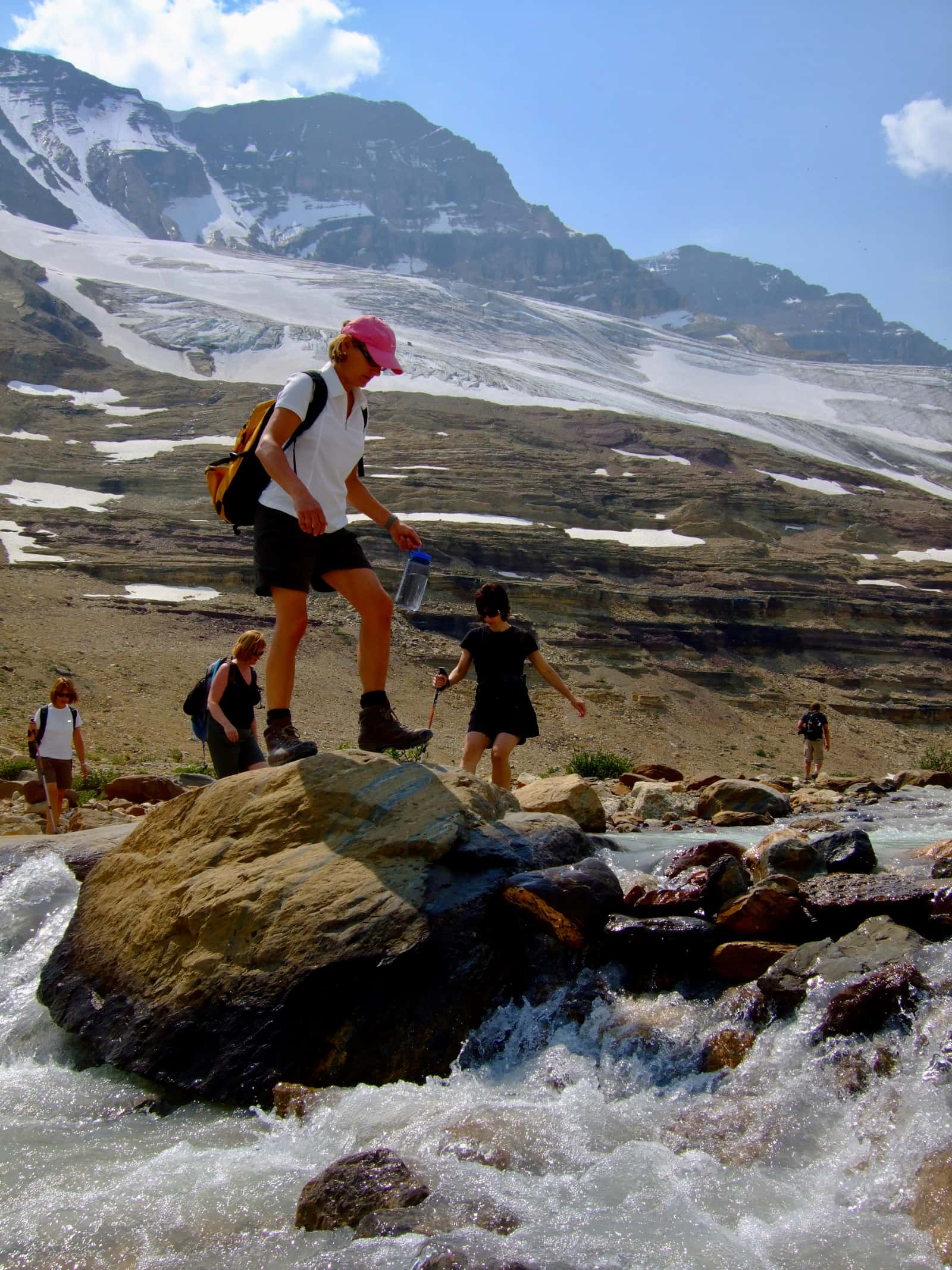 Group of hikers crossing fast flowing river
