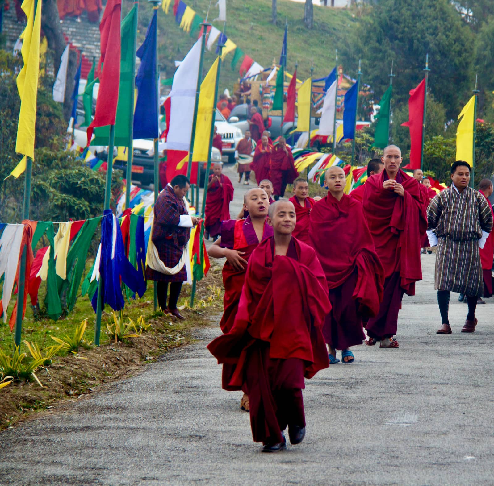 Group of monks in red robes walking on road