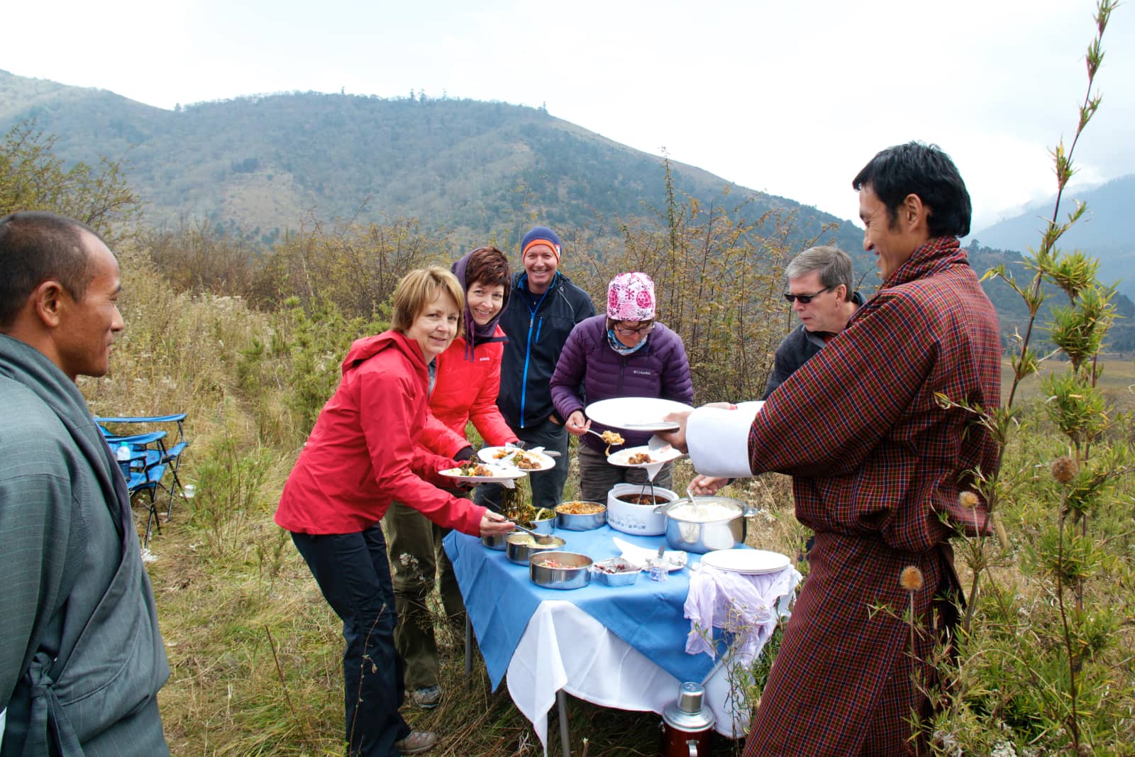 Group of people eating meal on hillside