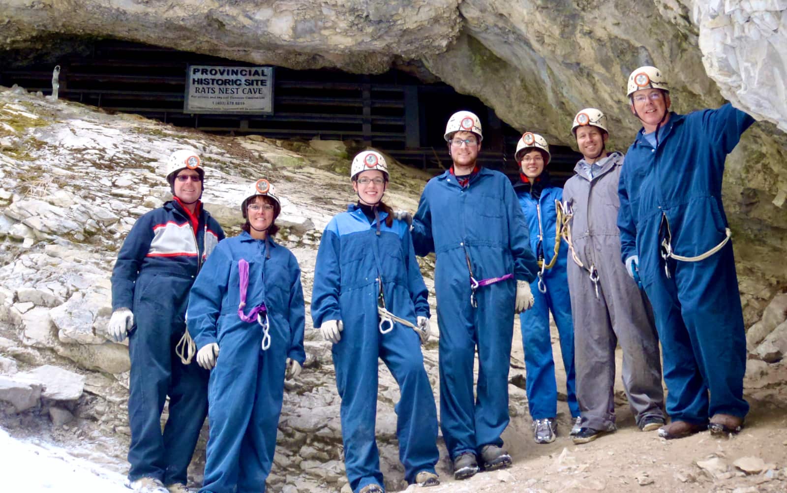Group of people in blue coveralls in foreground with Rats Nest cave entrance in background