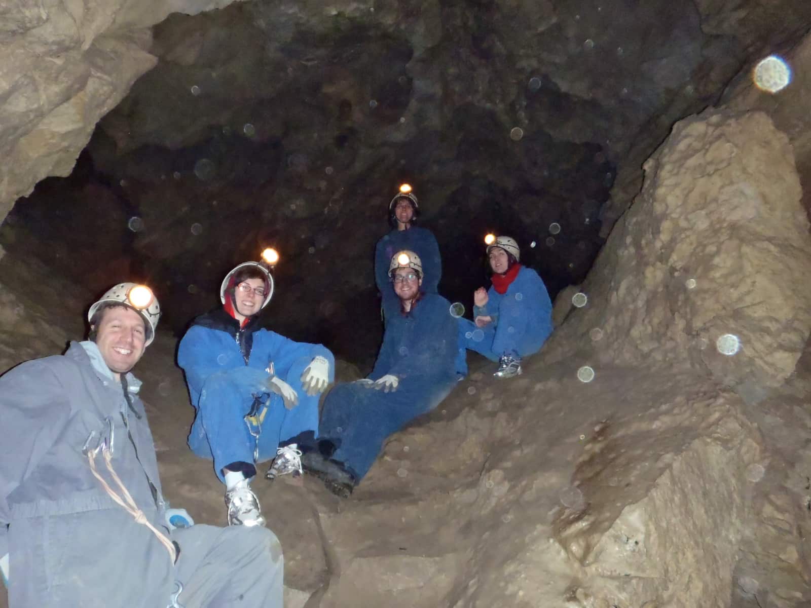 Group of people in blue coveralls sitting in cave