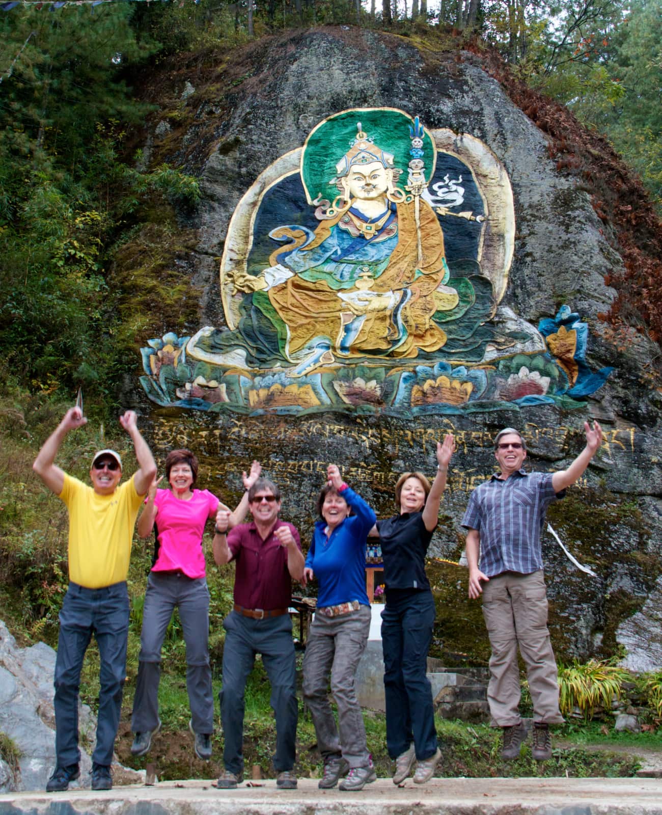 Group of people posing in front of Buddha mural