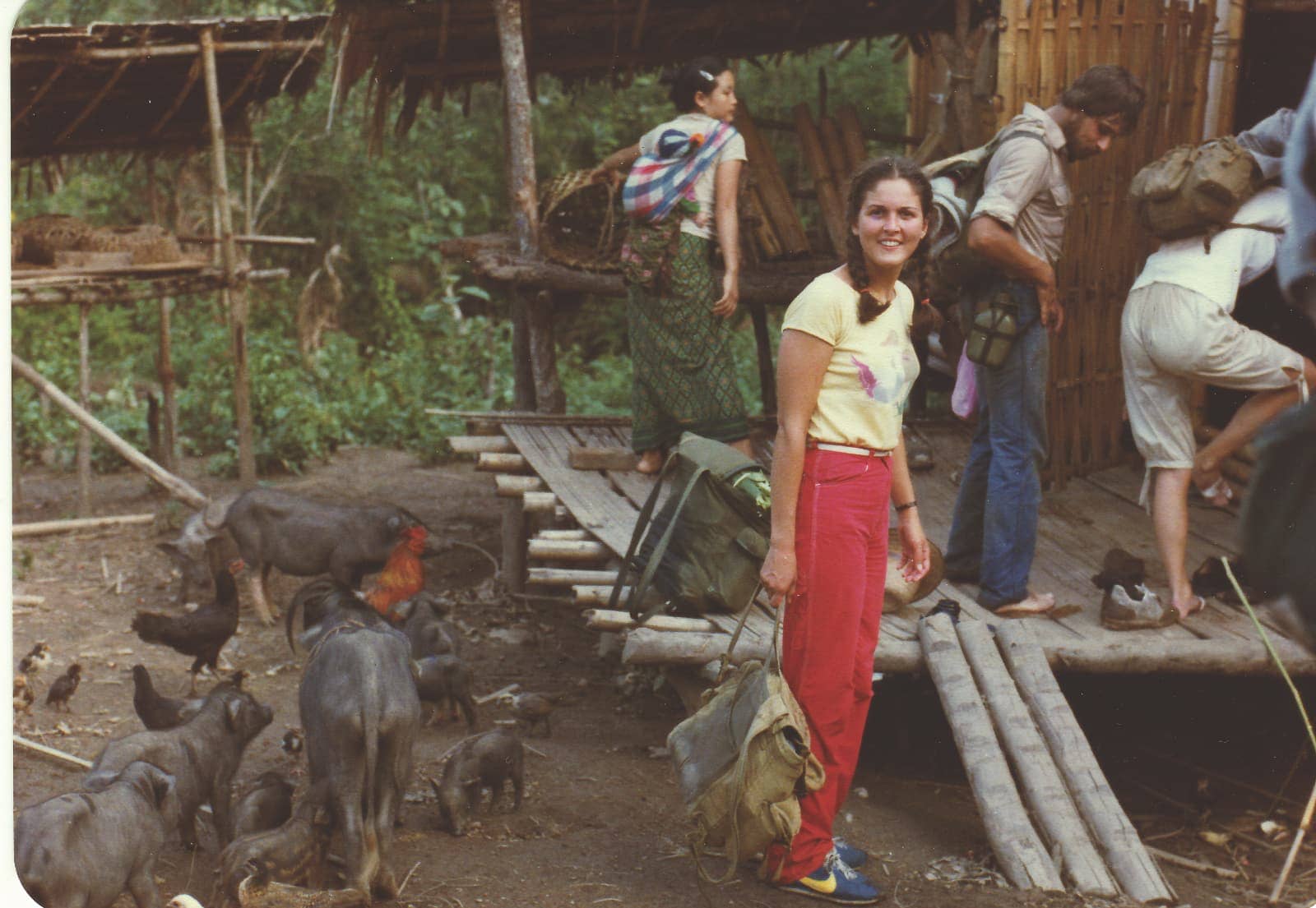 Group of people staying at village with chickens and pigs