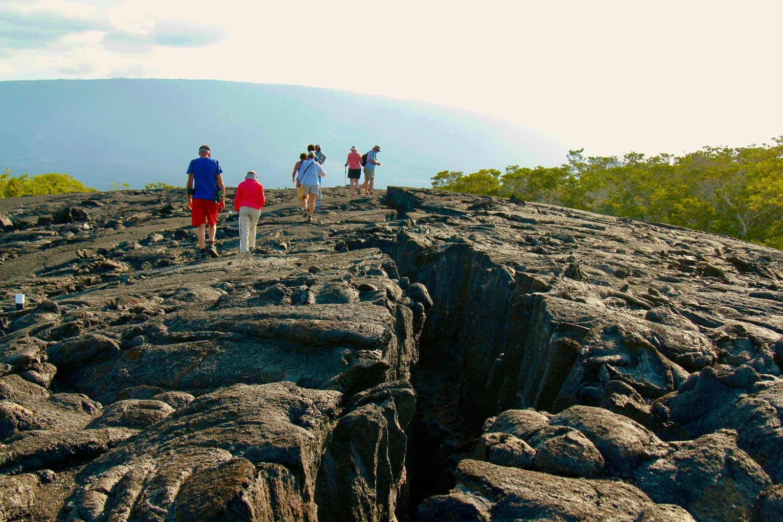 Group of people walking along lava formed rock