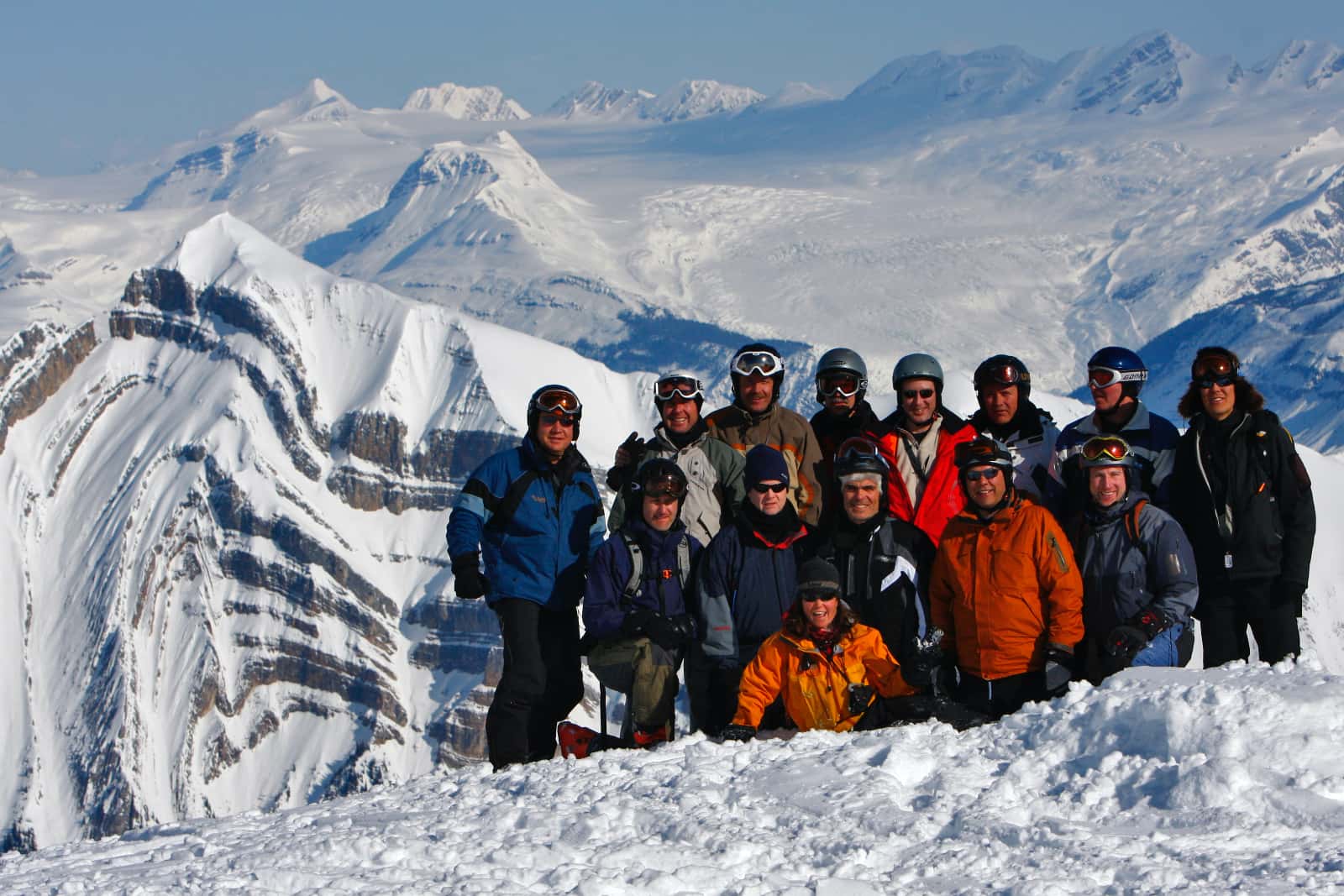 Group of skiers in foreground with snow covered mountains in background