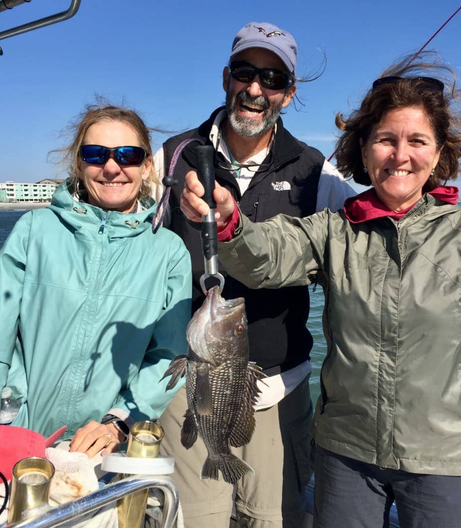 Man and two women smiling with fish in hand