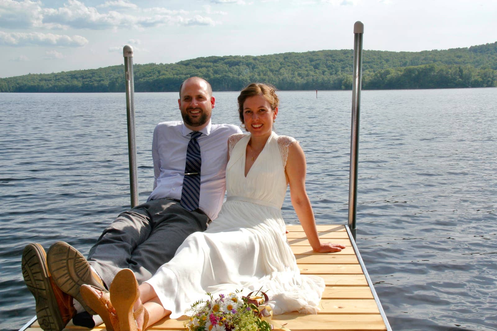 Man and woman in wedding clothes sitting on jetty