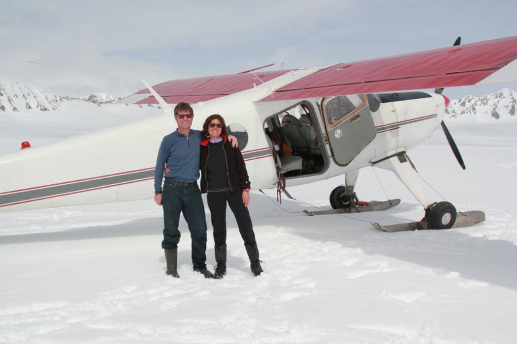 Man and woman posing in front of plane