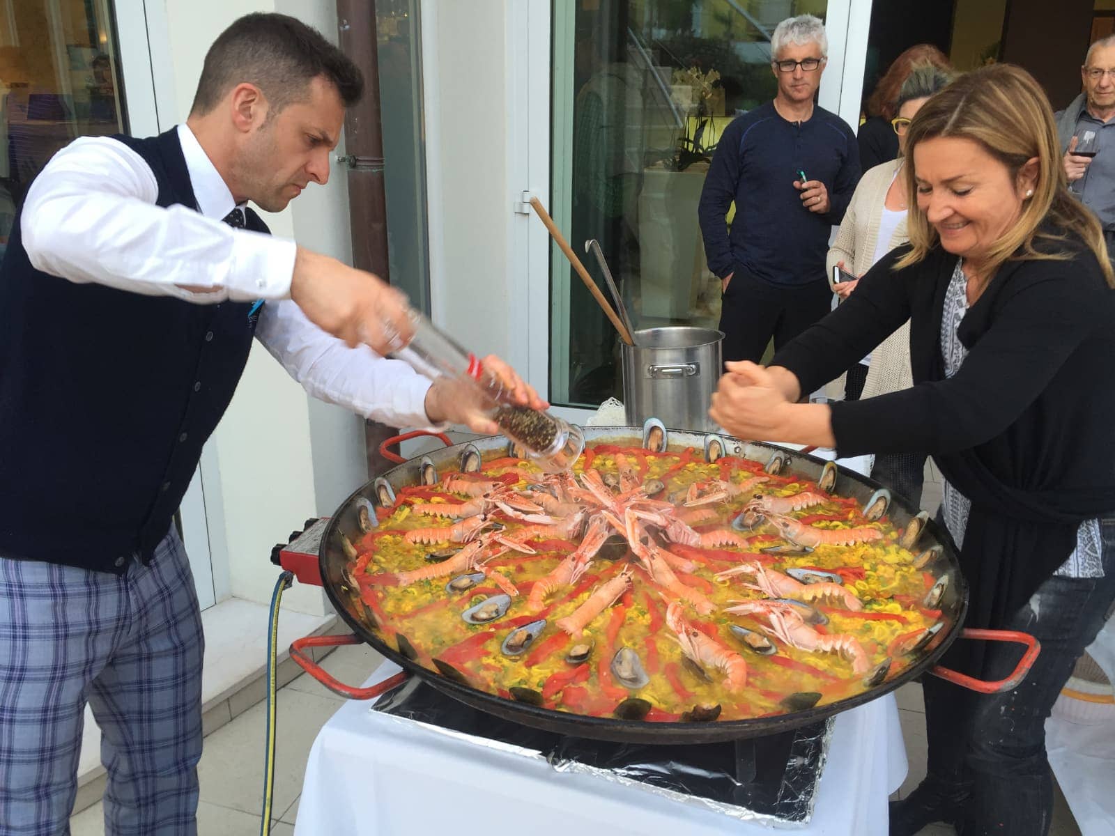 Man and woman seasoning large seafood dish