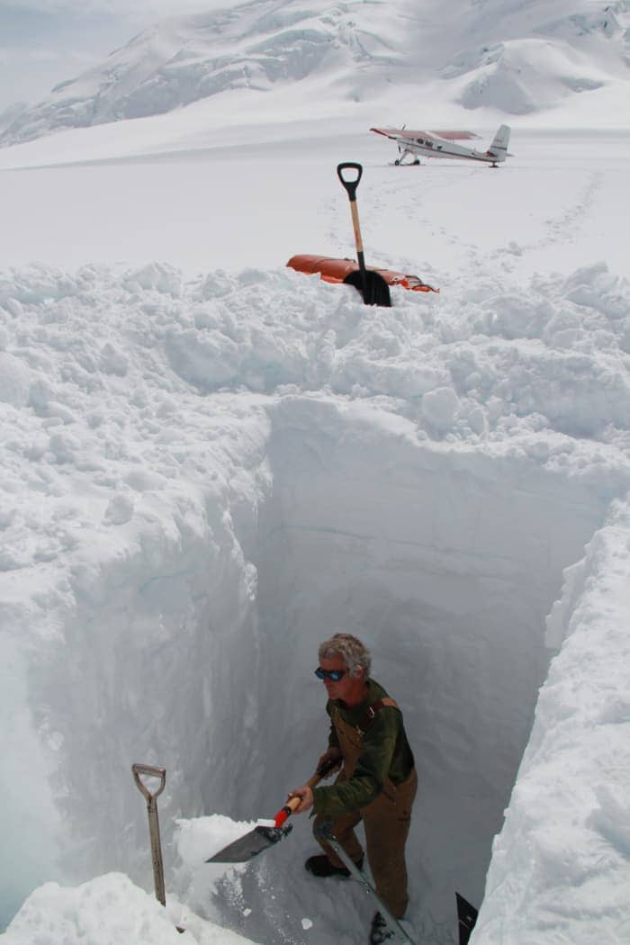 Man digging large hole in snow