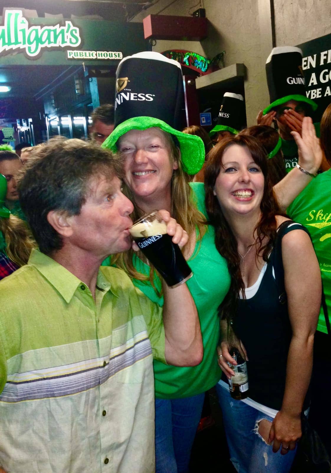 Man drinking Guinness beer with two women smiling