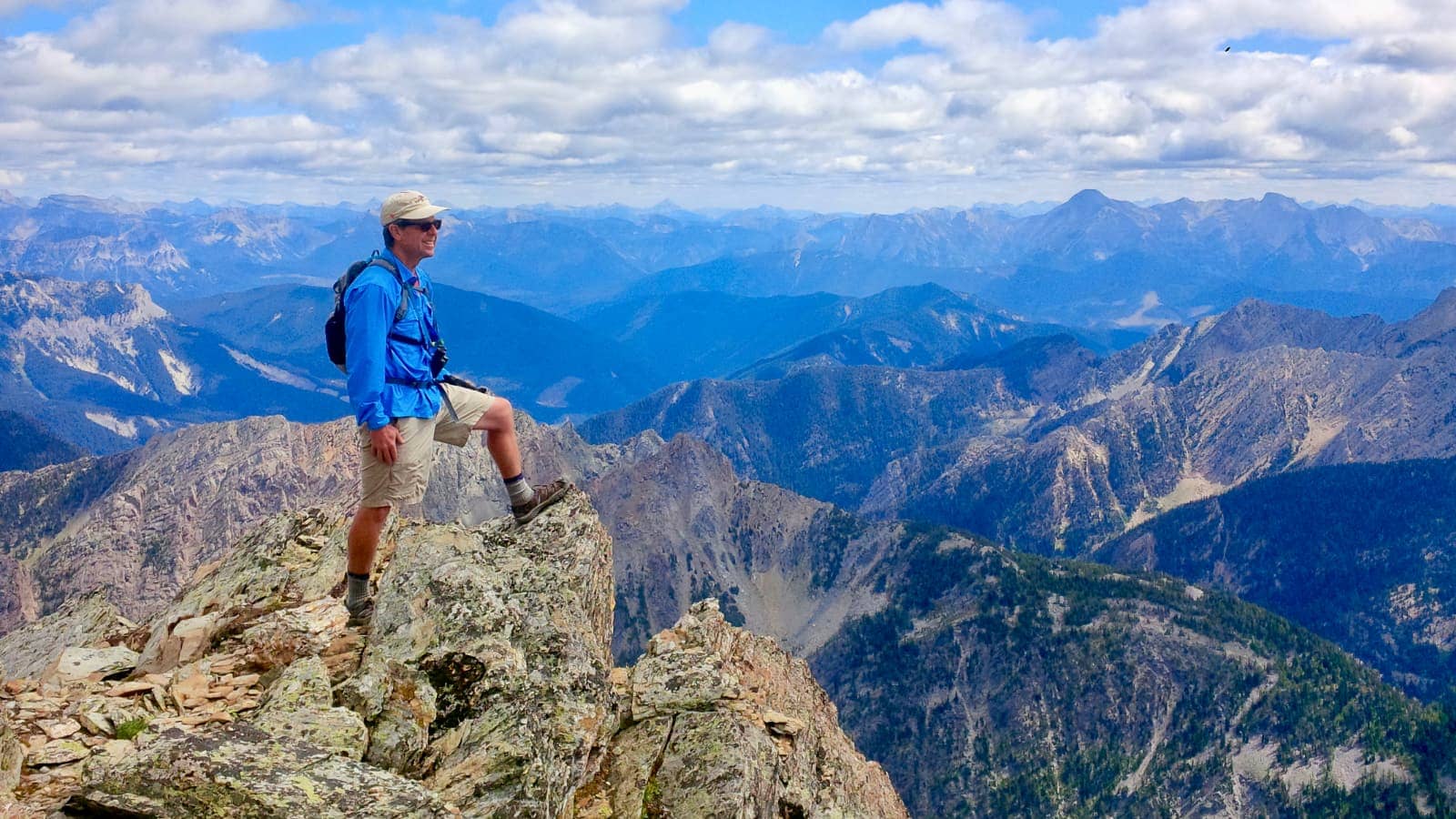 Man in blue jacket standing on mountain peak