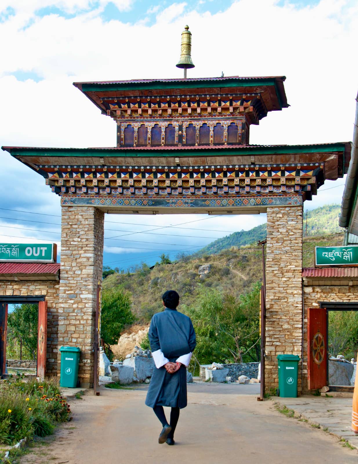 Man in blue robe walking towards brick archway