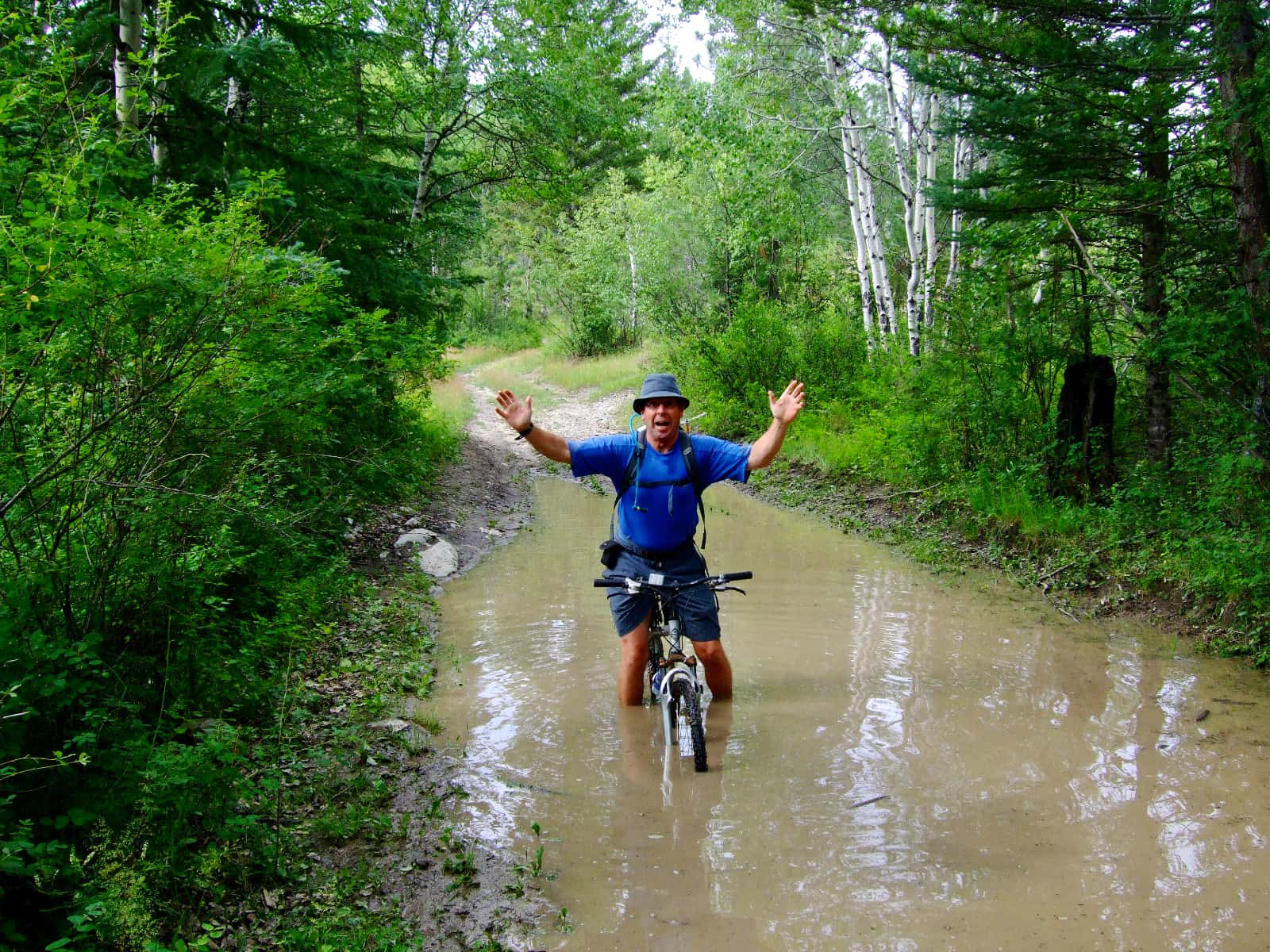 Man in blue shirt riding bicycle through deep water