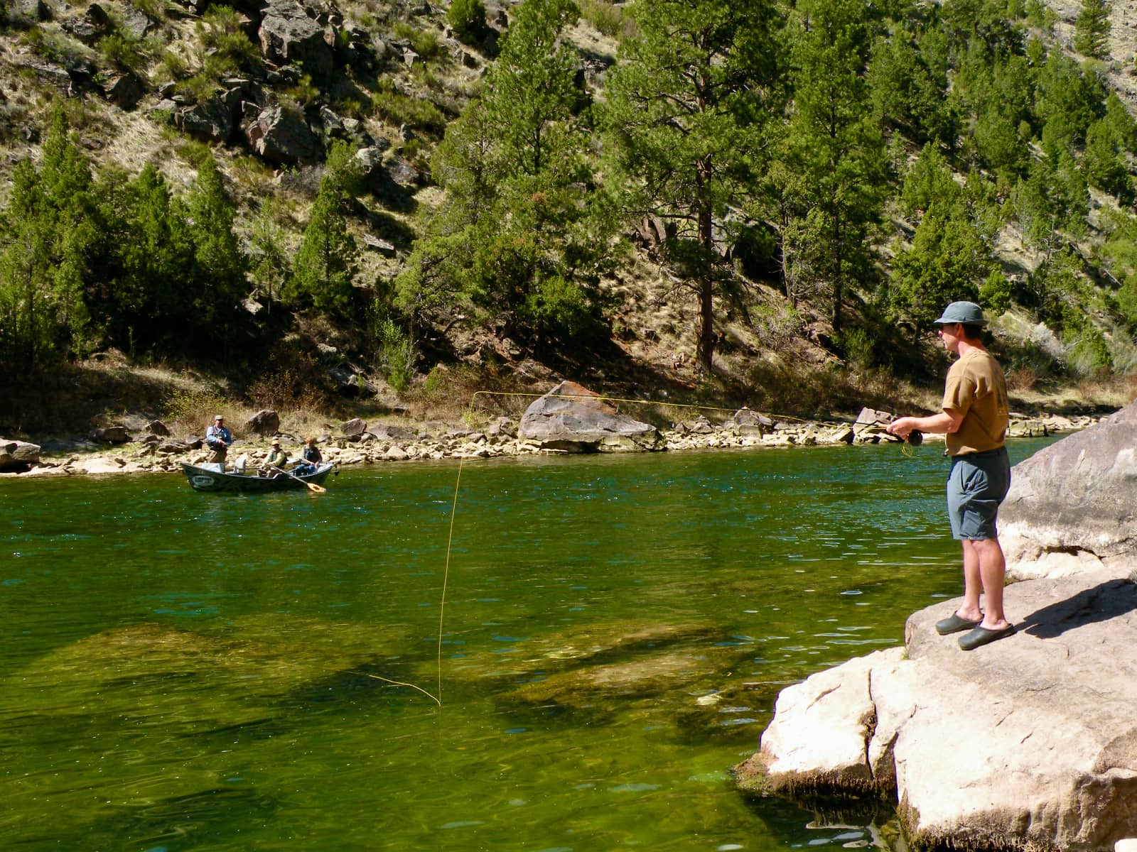 Man in gold shirt fishing on river bank
