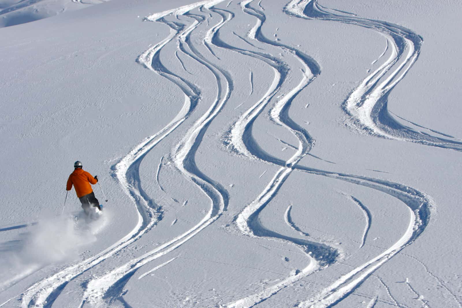 Man in orange jacket skiing down hill