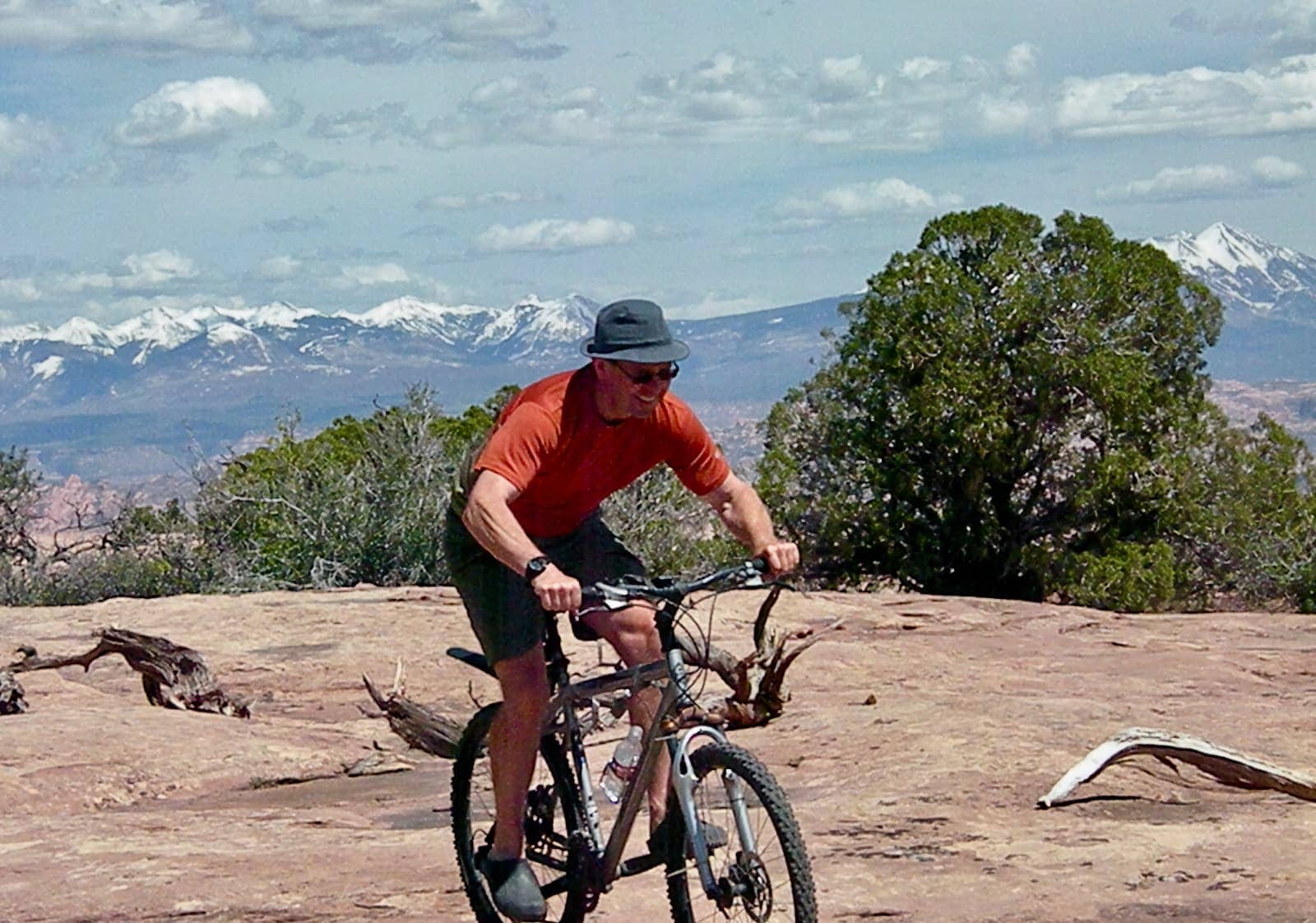 Man in orange shirt riding mountain bike