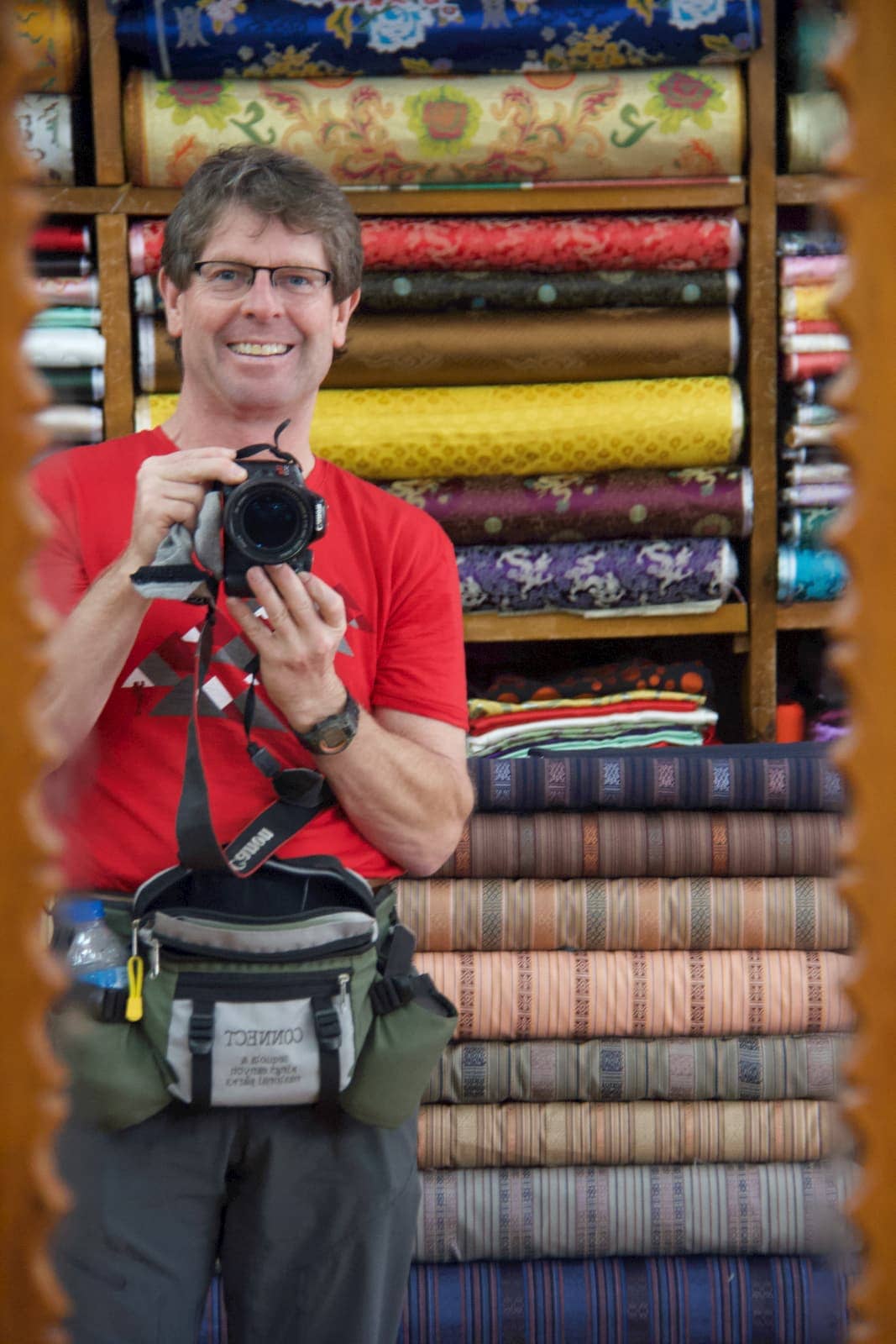 Man in red shirt taking photo of himself in mirror