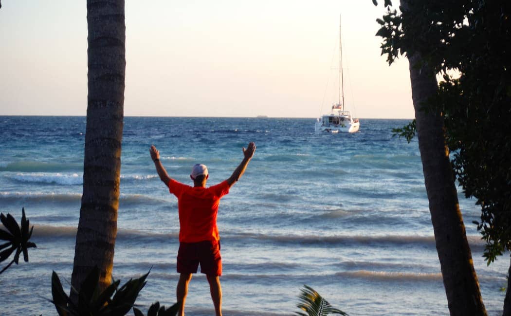 Man posing in front of ocean and sailboat