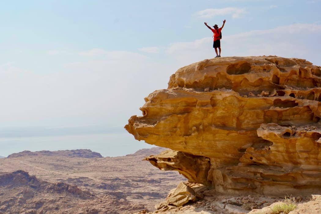 Man posing on top of rock in desert