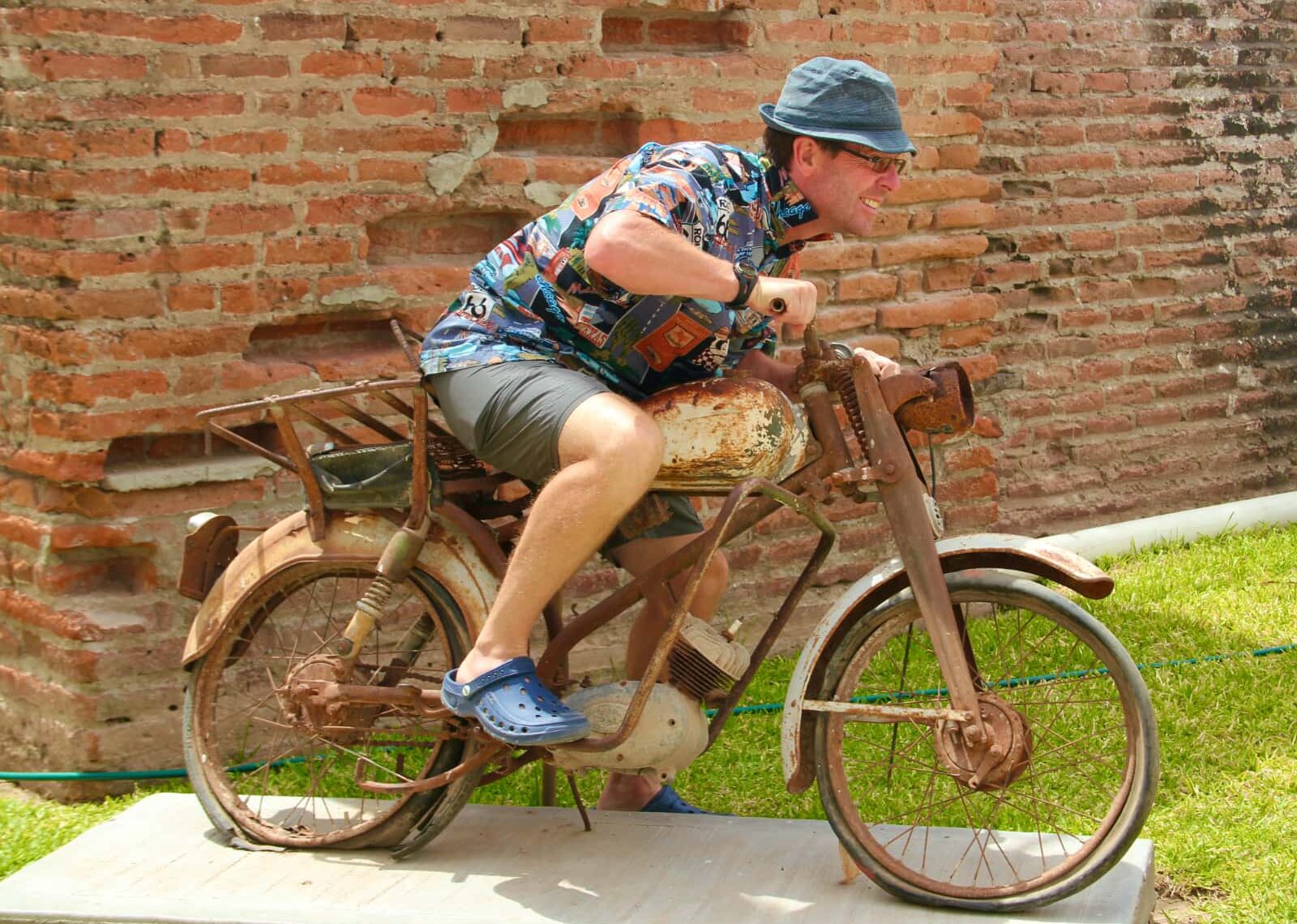 Man pretending to ride a worn out stationary motorcycle