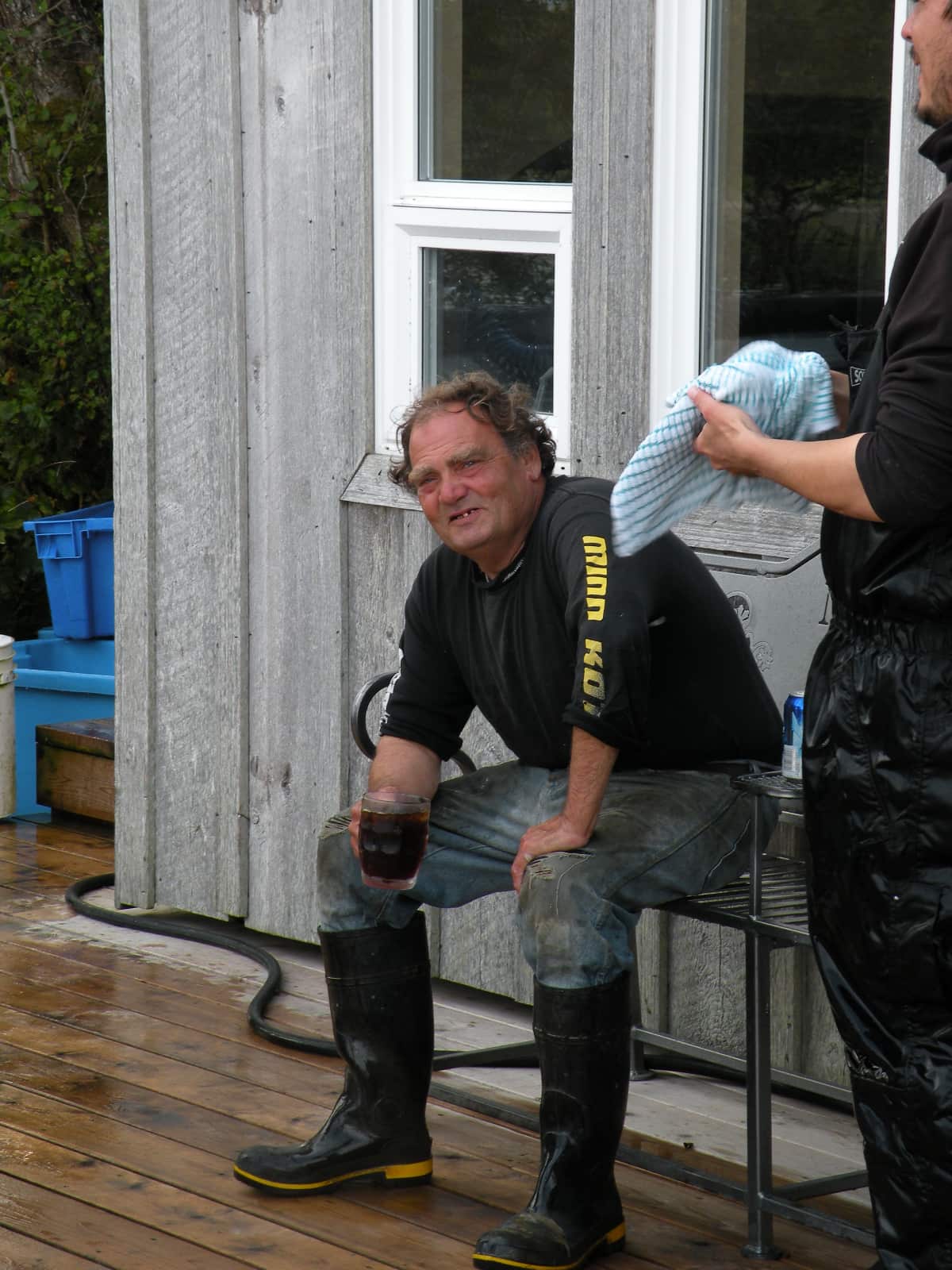 Man sitting on bench drinking a dark coloured beverage