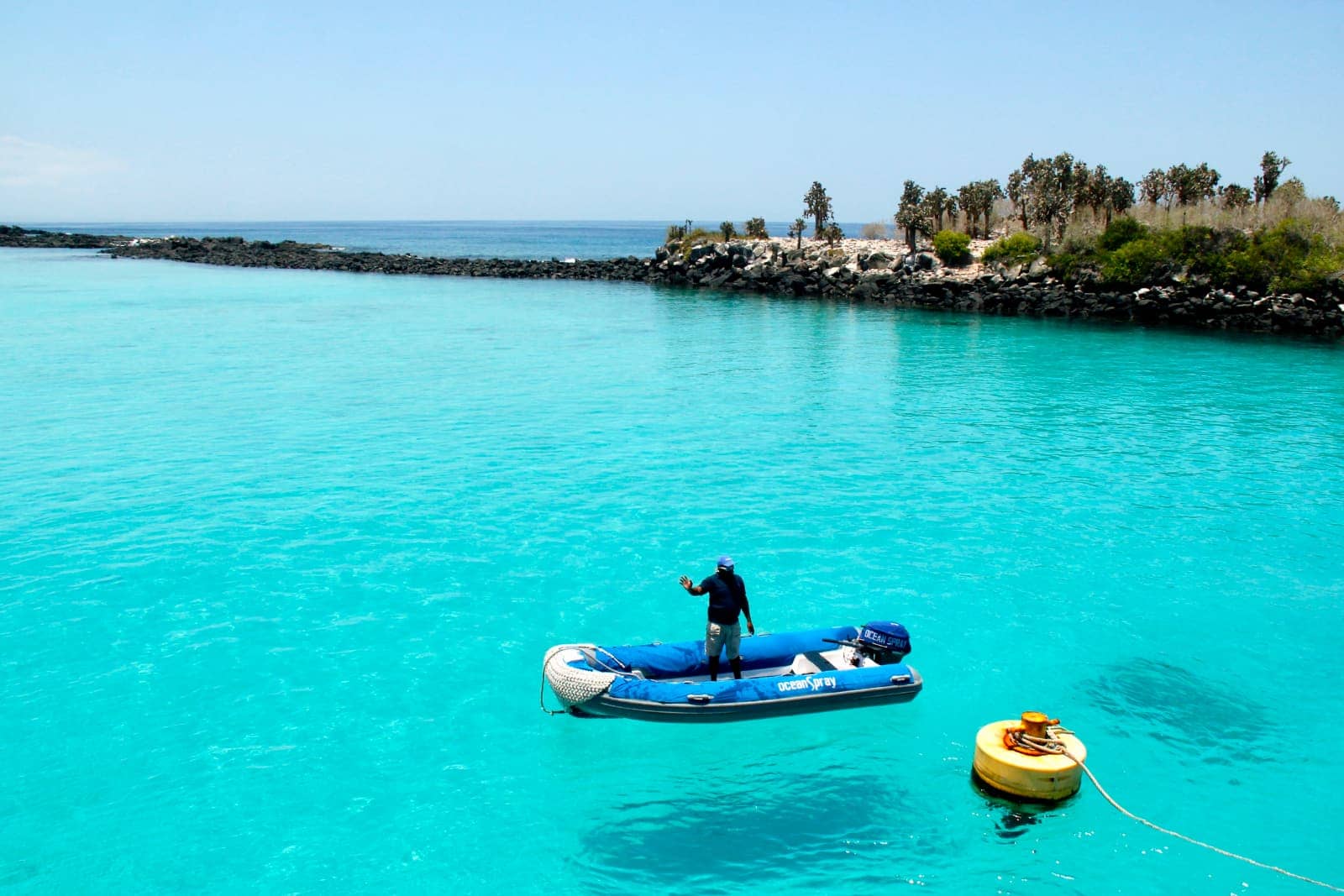 Man standing in blue zodiac boat in lagoon