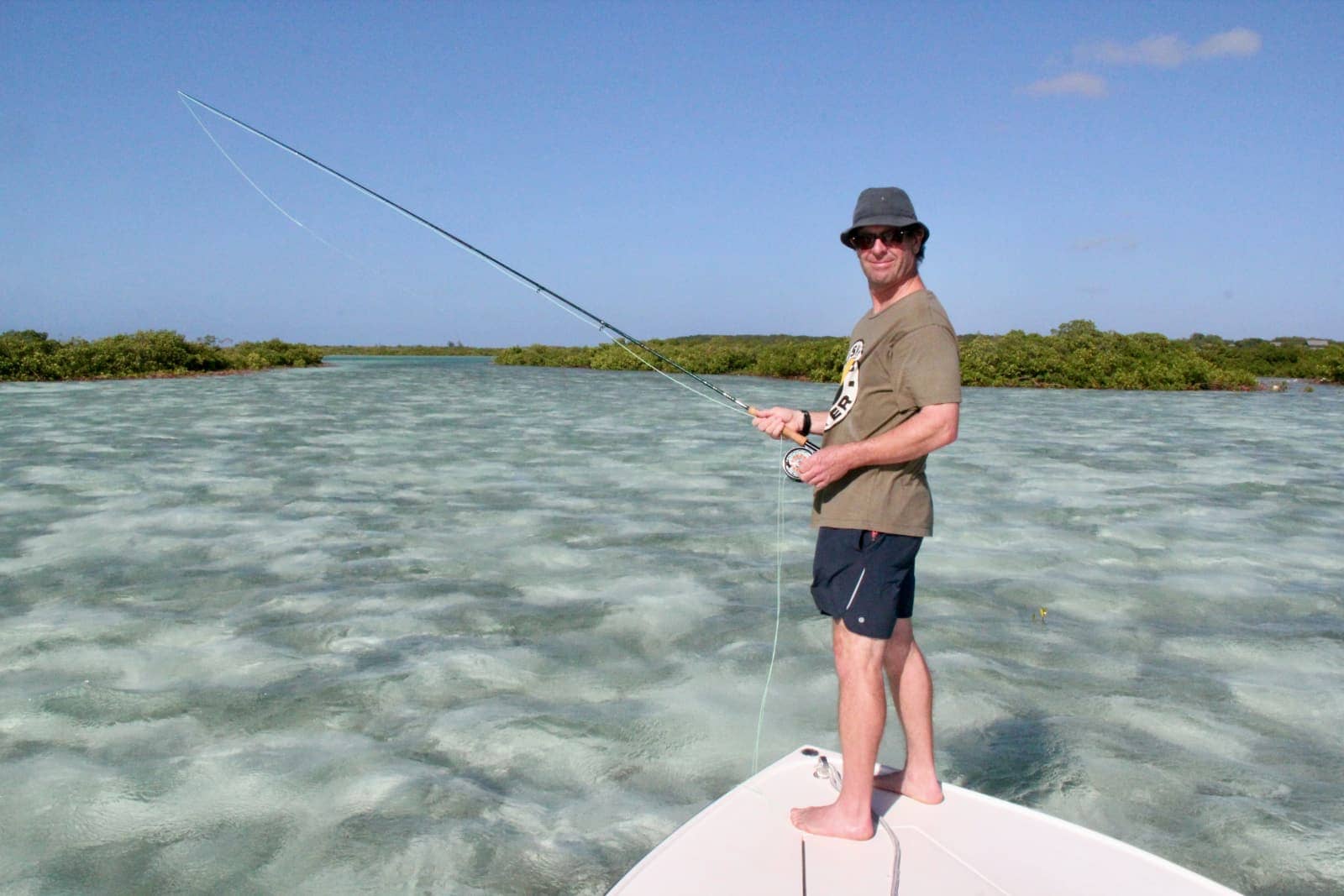 Man standing on front of small boat fishing