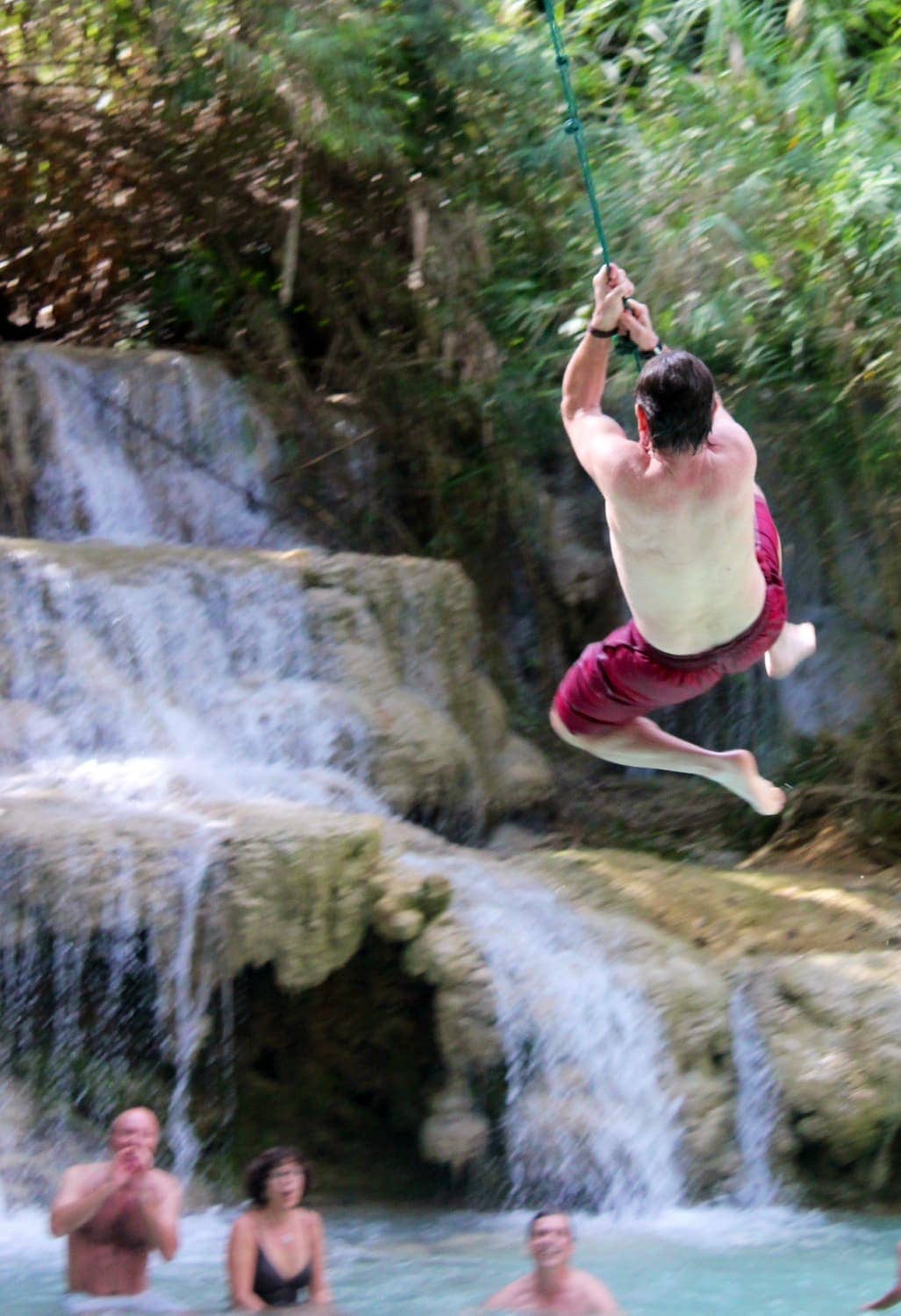 Man swinging on rope into water