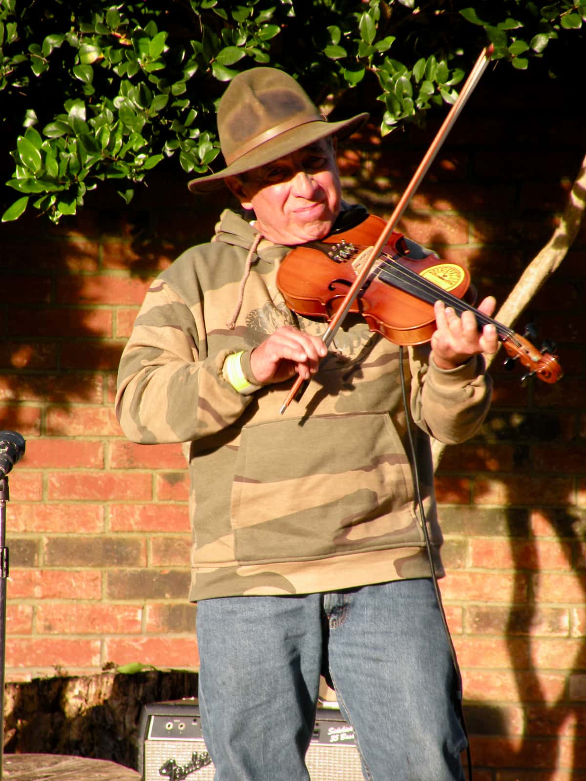 Man with green hat and sweater playing fiddle