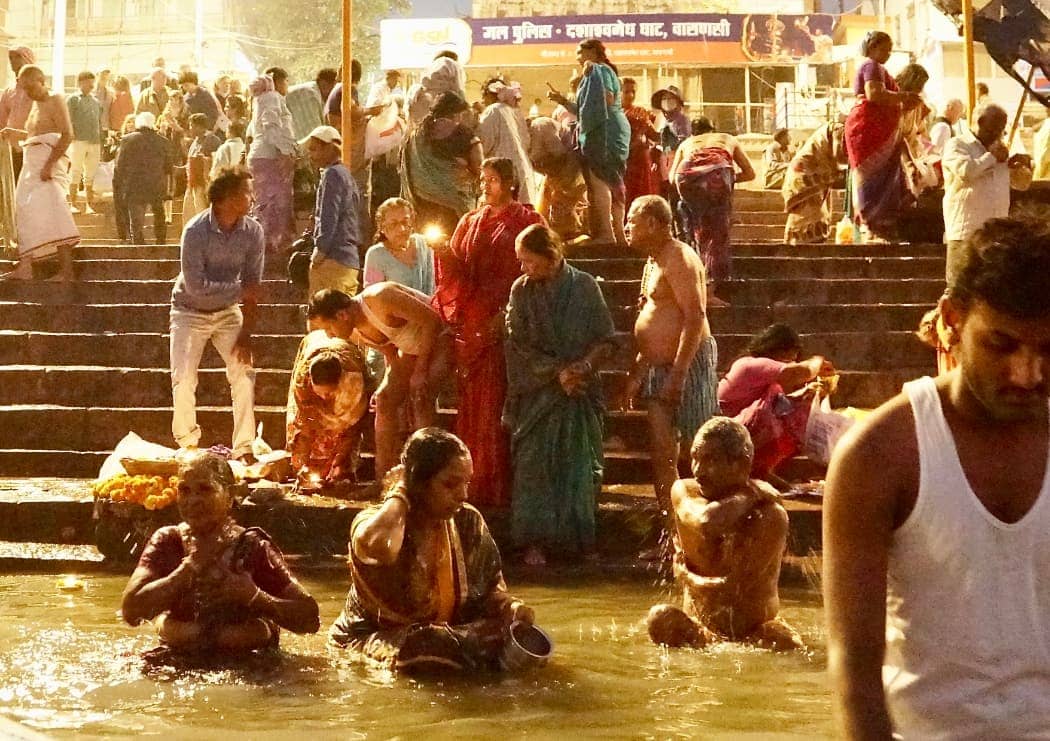 Men and women bathing in Ganges river at night