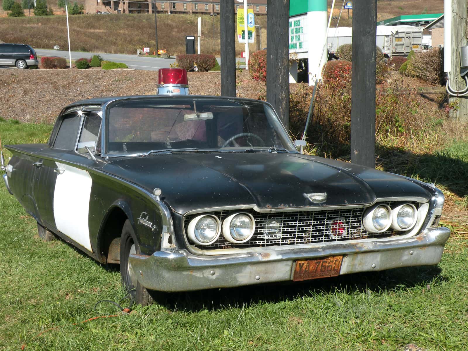Old black and white police car on grass