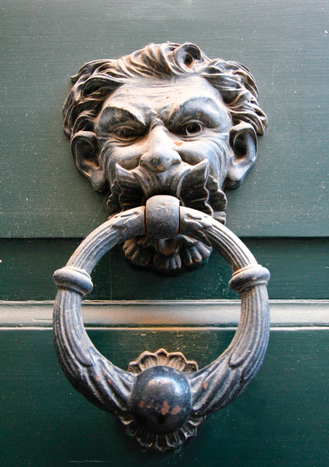 Old metal door knocker on green door