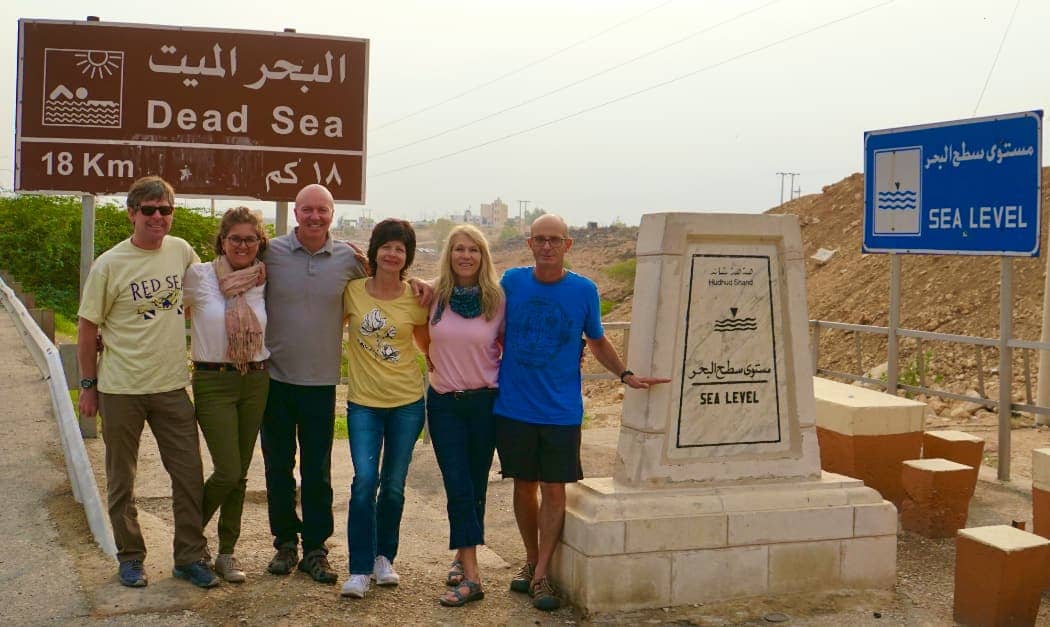People posing in front of Dead Sea sign