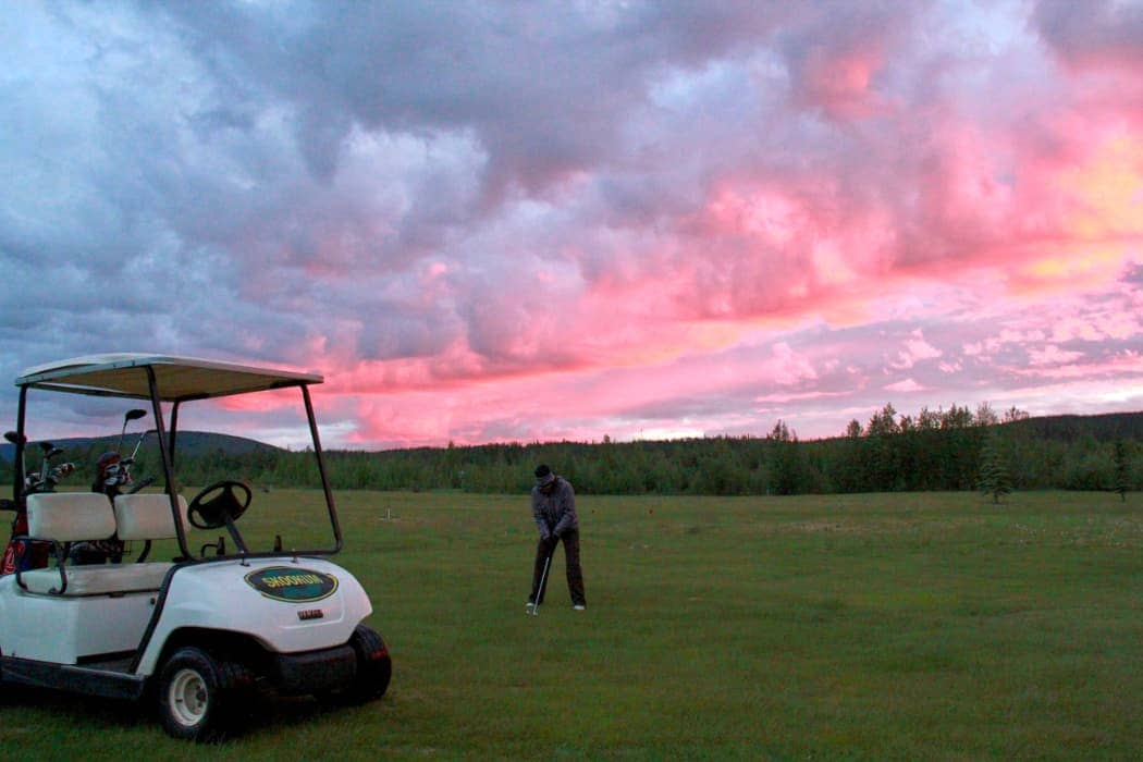 Person playing golf with pink clouds in background
